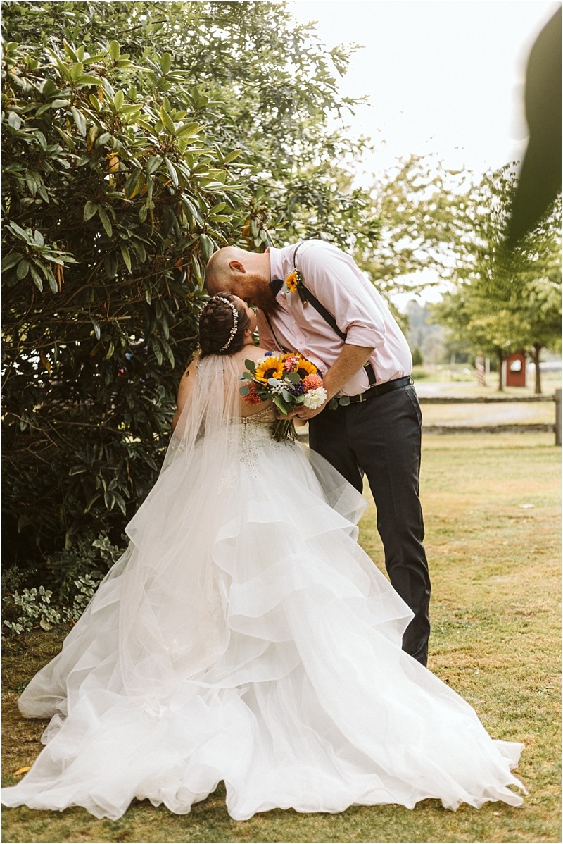Premier Snohomish & Seattle Wedding Photographer | GSquared Weddings Photography A bride in a flowing white gown holding a bouquet stands under a tree, as her groom gently kisses her forehead outdoors—a romantic Snohomish Seattle wedding engagement moment captured beautifully. 47.9129° N, 122.0982° W | Serving Snohomish, Seattle , Orlando & Beyond