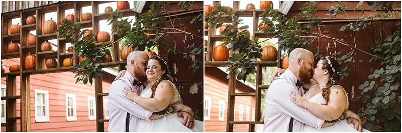 Premier Snohomish & Seattle Wedding Photographer | GSquared Weddings Photography A couple dressed in wedding attire embraces and kisses under a rustic wooden structure decorated with pumpkins, capturing a charming Snohomish wedding moment with a red building in the background. 47.9129° N, 122.0982° W | Serving Snohomish, Seattle , Orlando & Beyond