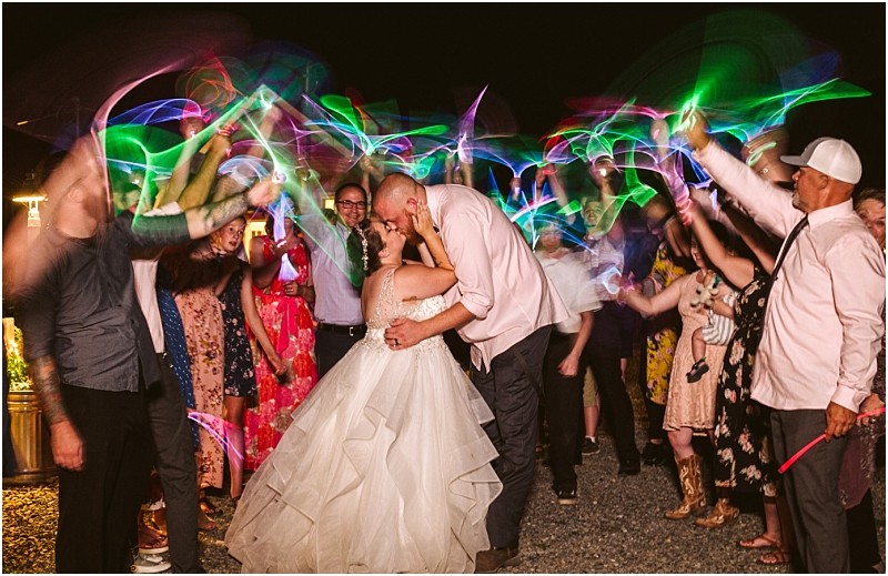 Premier Snohomish & Seattle Wedding Photographer | GSquared Weddings Photography A bride and groom kiss as they are surrounded by cheering guests waving colorful glow sticks in the air during a magical Snohomish wedding celebration. The bride wears a white gown and the groom is in a shirt and vest. 47.9129° N, 122.0982° W | Serving Snohomish, Seattle , Orlando & Beyond