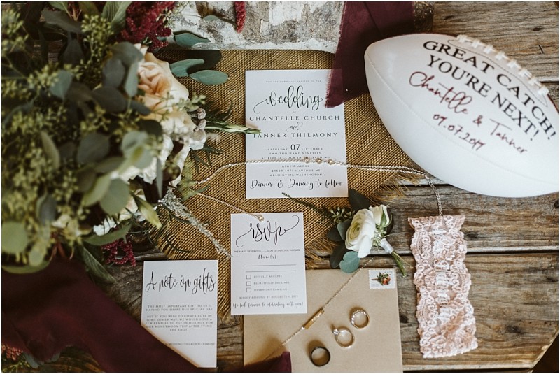 Premier Snohomish & Seattle Wedding Photographer | GSquared Weddings Photography Flat lay of Snohomish wedding items: invitation suite, RSVP card, note on gifts, lace garter, rings in a box, bouquet, boutonniere, and a signed football labeled Great Catch! You’re Next! featuring Seattle engagement details. 47.9129° N, 122.0982° W | Serving Snohomish, Seattle , Orlando & Beyond