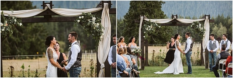 Premier Snohomish & Seattle Wedding Photographer | GSquared Weddings Photography A bride and groom stand under a rustic wooden arch with white drapes and flowers, exchanging vows outdoors in the mountains near Snohomish. Bridesmaids, groomsmen, and guests look on during this beautiful Seattle wedding. 47.9129° N, 122.0982° W | Serving Snohomish, Seattle , Orlando & Beyond