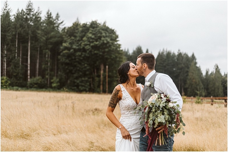 Premier Snohomish & Seattle Wedding Photographer | GSquared Weddings Photography A bride and groom share a romantic kiss in a field of tall grass near Snohomish. Surrounded by trees, the bride in a white lace gown and bouquet, and the groom in vest and tie, capture classic Seattle wedding engagement charm. 47.9129° N, 122.0982° W | Serving Snohomish, Seattle , Orlando & Beyond