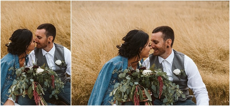 Premier Snohomish & Seattle Wedding Photographer | GSquared Weddings Photography A couple sits closely together in a golden grassy field near Snohomish, smiling at each other. The woman holds a bouquet of greenery and white flowers, wearing a denim jacket—perfect for their Seattle wedding engagement session. 47.9129° N, 122.0982° W | Serving Snohomish, Seattle , Orlando & Beyond