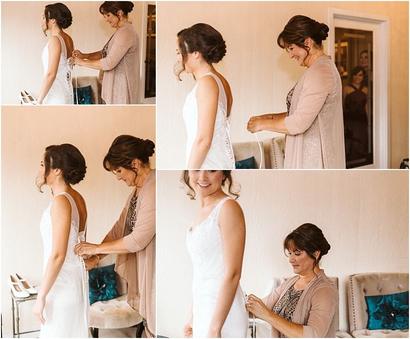 Premier Snohomish & Seattle Wedding Photographer | GSquared Weddings Photography In a softly lit room near Snohomish, a woman helps a bride button up her wedding dress as they both smile with happiness. Other women in the background watch and share in the joy of this Seattle wedding moment. 47.9129° N, 122.0982° W | Serving Snohomish, Seattle , Orlando & Beyond