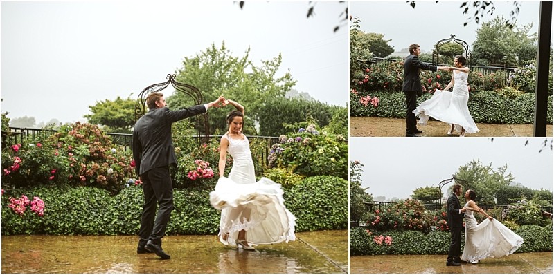 Premier Snohomish & Seattle Wedding Photographer | GSquared Weddings Photography A bride and groom dance joyfully in the rain on a stone patio surrounded by lush greenery and colorful flowers—an unforgettable Snohomish Seattle wedding moment as the bride’s white dress swirls while they twirl together. 47.9129° N, 122.0982° W | Serving Snohomish, Seattle , Orlando & Beyond