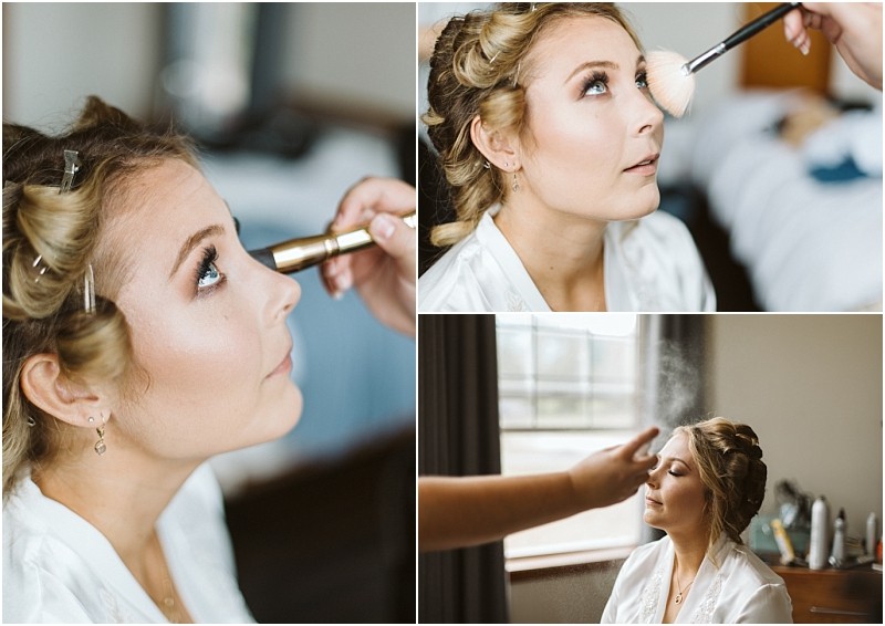 Premier Snohomish & Seattle Wedding Photographer | GSquared Weddings Photography A woman with curled hair in rollers gets her makeup done for her Snohomish wedding. She sits in a white robe while a makeup artist applies mascara, blush, and setting spray in a softly lit room. 47.9129° N, 122.0982° W | Serving Snohomish, Seattle , Orlando & Beyond