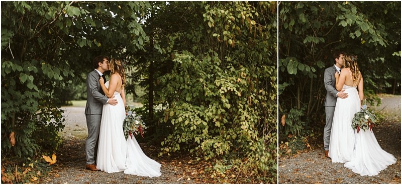 Premier Snohomish & Seattle Wedding Photographer | GSquared Weddings Photography A bride and groom share an embrace and kiss under lush green trees on a gravel path, celebrating their Snohomish wedding. The bride wears a white dress with a bouquet; the groom is dressed in a gray suit. 47.9129° N, 122.0982° W | Serving Snohomish, Seattle , Orlando & Beyond