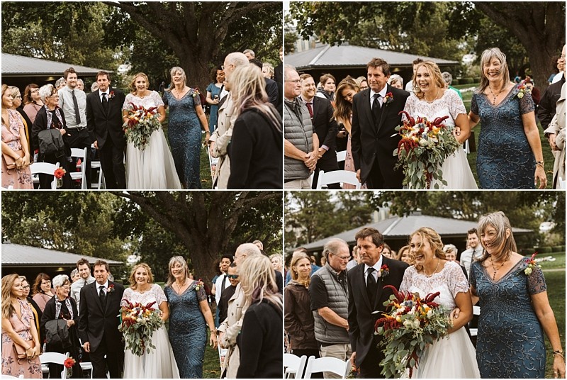Premier Snohomish & Seattle Wedding Photographer | GSquared Weddings Photography A bride walks down the outdoor aisle on her Snohomish wedding day, accompanied by her parents. Guests, some standing and some seated, watch and smile. The scene is joyful, surrounded by trees and greenery. 47.9129° N, 122.0982° W | Serving Snohomish, Seattle , Orlando & Beyond