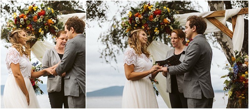Premier Snohomish & Seattle Wedding Photographer | GSquared Weddings Photography A bride and groom stand under a floral arch outdoors in Snohomish, holding hands and exchanging vows with an officiant, while mountains and water appear in the background—a stunning Seattle wedding moment. 47.9129° N, 122.0982° W | Serving Snohomish, Seattle , Orlando & Beyond