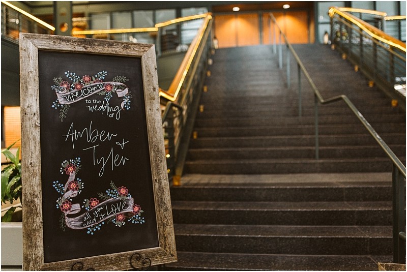 Premier Snohomish & Seattle Wedding Photographer | GSquared Weddings Photography A chalkboard wedding sign with floral decorations reads “Welcome to the wedding of Amber & Tyler, all you need is love,” and stands at the base of wide, carpeted stairs—perfect for a romantic Snohomish Seattle wedding or engagement celebration. 47.9129° N, 122.0982° W | Serving Snohomish, Seattle , Orlando & Beyond