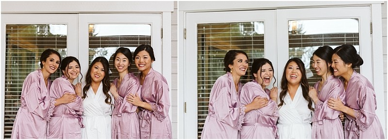 Premier Snohomish & Seattle Wedding Photographer | GSquared Weddings Photography Five women in matching robes, four in lilac and one in white, stand closely together smiling and laughing—capturing a joyful moment before a Snohomish Seattle wedding or engagement—in front of glass doors with white frames. 47.9129° N, 122.0982° W | Serving Snohomish, Seattle , Orlando & Beyond