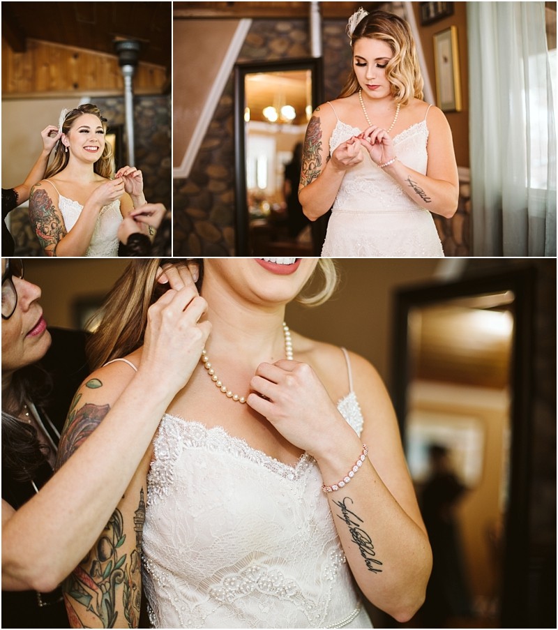 Premier Snohomish & Seattle Wedding Photographer | GSquared Weddings Photography A bride in a lace wedding dress smiles as she puts on earrings and a necklace, assisted by another person, in a cozy, wood-paneled room with soft lighting—capturing a warm Snohomish Seattle wedding moment. 47.9129° N, 122.0982° W | Serving Snohomish, Seattle , Orlando & Beyond