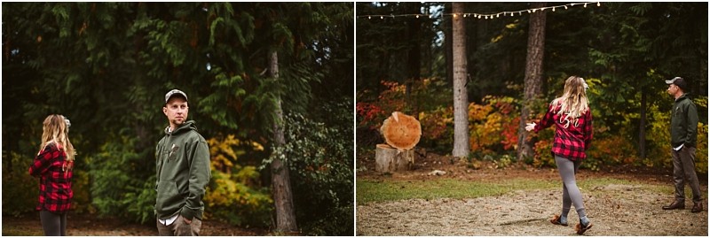 Premier Snohomish & Seattle Wedding Photographer | GSquared Weddings Photography Two people outdoors in a wooded area. On the left, a man in a green hoodie and cap stands beside a woman in a red plaid shirt. On the right, she walks toward wooden targets while he watches—perfect for a rustic Snohomish or Seattle engagement session. String lights glow above. 47.9129° N, 122.0982° W | Serving Snohomish, Seattle , Orlando & Beyond