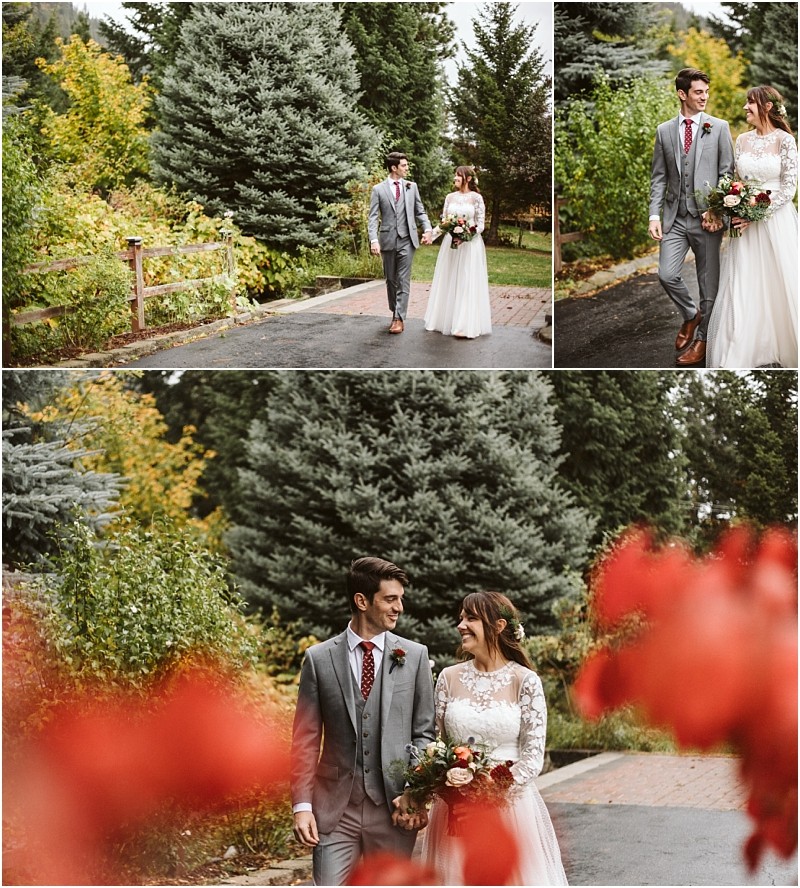 Premier Snohomish & Seattle Wedding Photographer | GSquared Weddings Photography A bride in a white dress and groom in a gray suit walk hand-in-hand outdoors at a Snohomish Seattle wedding, surrounded by greenery and autumn trees, smiling at each other with red flowers in the foreground. 47.9129° N, 122.0982° W | Serving Snohomish, Seattle , Orlando & Beyond