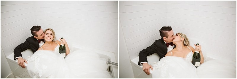 Premier Snohomish & Seattle Wedding Photographer | GSquared Weddings Photography A newlywed couple in wedding attire sit together in a white bathtub at their Snohomish Seattle wedding; the bride holds a champagne bottle and makes a playful face as the groom kisses her cheek, then kisses her lips. 47.9129° N, 122.0982° W | Serving Snohomish, Seattle , Orlando & Beyond