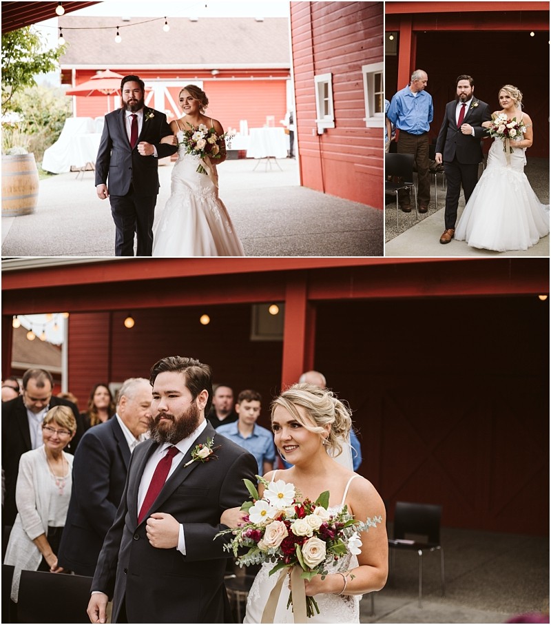 Premier Snohomish & Seattle Wedding Photographer | GSquared Weddings Photography A bride in a white dress and a man in a suit with a red tie walk arm in arm at an outdoor Snohomish wedding venue with a red barn, surrounded by guests. The bride holds a bouquet of flowers and smiles. 47.9129° N, 122.0982° W | Serving Snohomish, Seattle , Orlando & Beyond