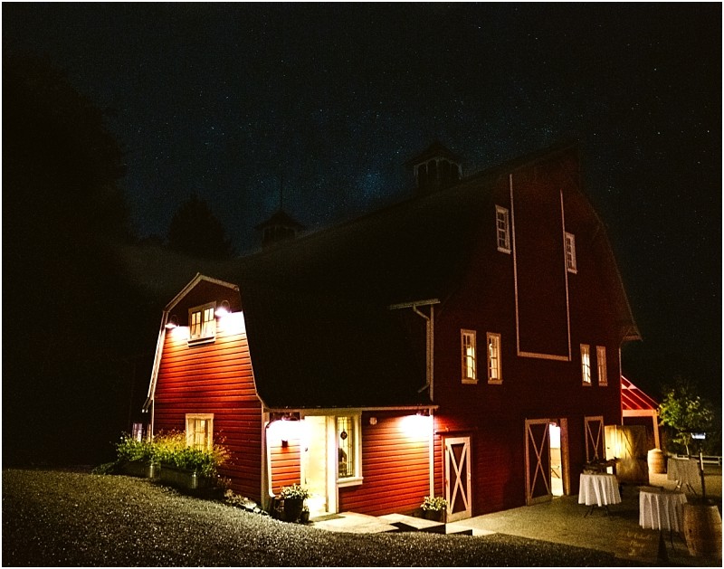 Premier Snohomish & Seattle Wedding Photographer | GSquared Weddings Photography A large red barn near Snohomish stands warmly lit against a dark, starry night sky, with potted plants by the entrance and white-clothed tables set up outside for a charming Seattle wedding or engagement celebration. 47.9129° N, 122.0982° W | Serving Snohomish, Seattle , Orlando & Beyond