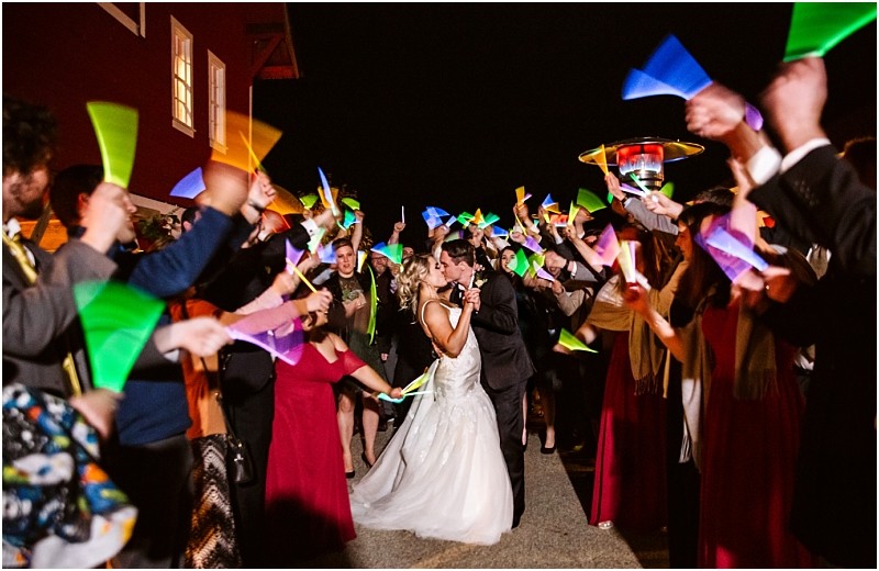 Premier Snohomish & Seattle Wedding Photographer | GSquared Weddings Photography A bride and groom kiss while walking through a crowd of guests holding colorful glow sticks in celebration at their Snohomish Seattle wedding. Everyone looks joyful, creating a festive atmosphere perfect for this unforgettable engagement. 47.9129° N, 122.0982° W | Serving Snohomish, Seattle , Orlando & Beyond