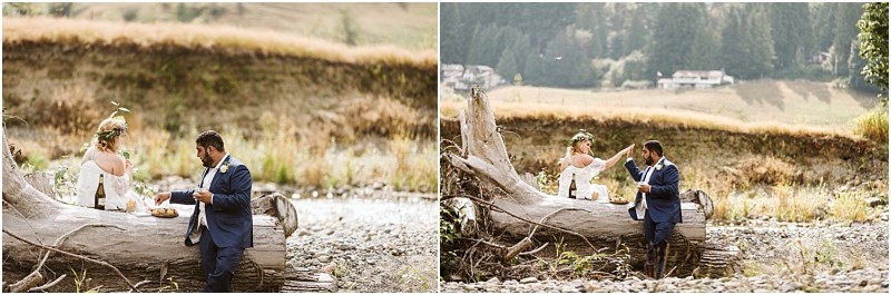 Premier Snohomish & Seattle Wedding Photographer | GSquared Weddings Photography A couple dressed in wedding attire shares a picnic on a large fallen tree trunk in a scenic, rustic outdoor setting—perfect for a Snohomish Seattle wedding engagement—with grass, rocks, and distant trees. 47.9129° N, 122.0982° W | Serving Snohomish, Seattle , Orlando & Beyond