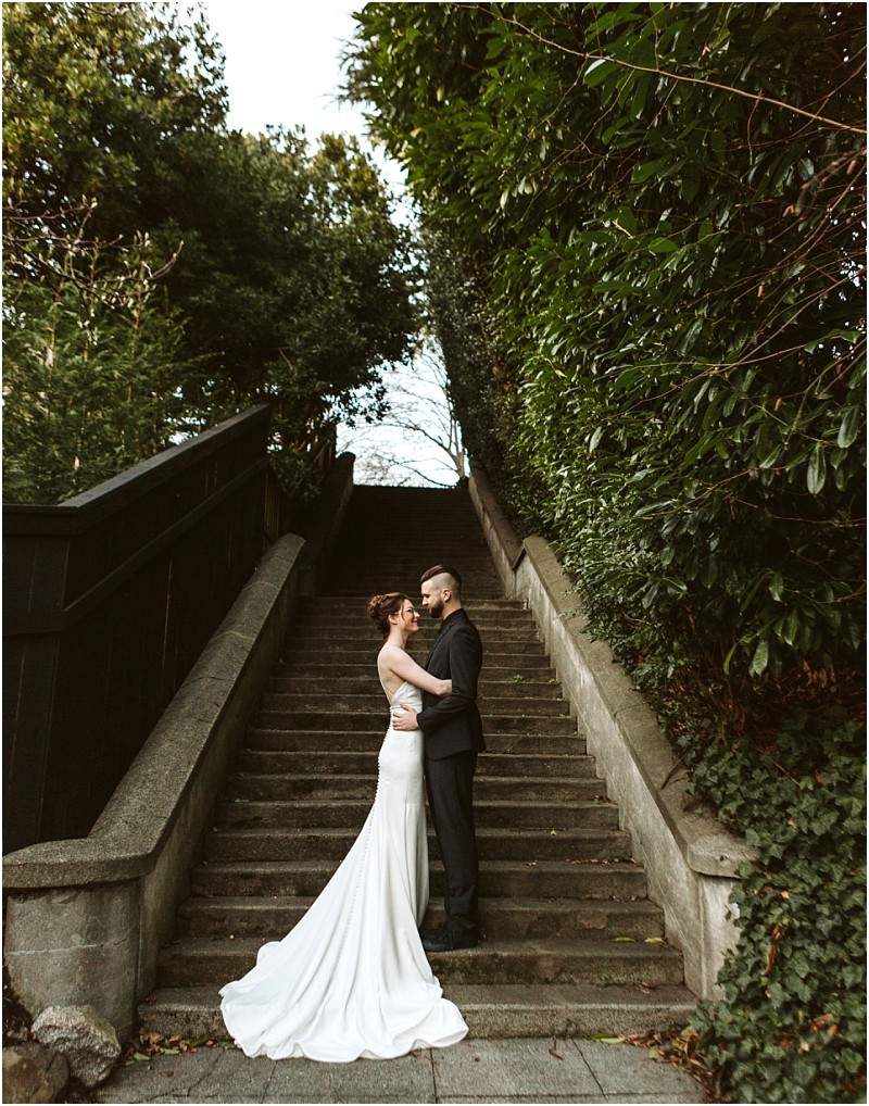 Premier Snohomish & Seattle Wedding Photographer | GSquared Weddings Photography A bride and groom embrace on outdoor stone steps, surrounded by greenery and trees at a tranquil Snohomish setting. The bride in a long white dress and the groom in a dark suit gaze at each other lovingly after their Seattle wedding engagement. 47.9129° N, 122.0982° W | Serving Snohomish, Seattle , Orlando & Beyond