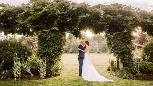A bride and groom embrace and kiss under a large leafy green arch in a garden setting at one of the enchanting Washington wedding venues with sunlight filtering through the trees in the background Snohomish Wedding Photography A bride and groom embrace and kiss under a large leafy green arch in a garden setting at one of the enchanting Washington wedding venues with sunlight filtering through the trees in the background Snohomish Wedding Photography