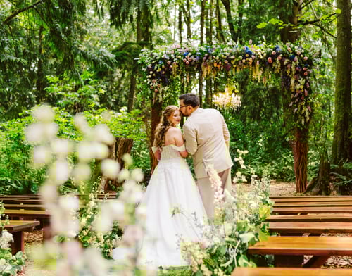 A bride and groom stand closely together under a flowercovered arch in a forest at one of the stunning Snohomish wedding venues surrounded by greenery and wooden benches the bride is in a white dress and the groom in a beige suit Snohomish Wedding Photography A bride and groom stand closely together under a flower covered arch in a forest at one of the stunning Snohomish wedding venues surrounded by greenery and wooden benches the bride is in a white dress and the groom in a beige suit Snohomish Wedding Photography