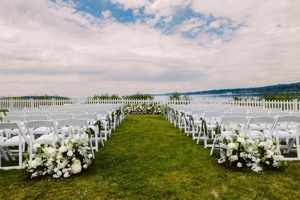 Rows of white chairs arranged for a Washington wedding ceremony on a grassy lawn decorated with white flowers overlooking a body of water with a picket fence and a partly cloudy skyone of the most picturesque Washington wedding venues Snohomish Wedding Photography Rows of white chairs arranged for a Washington wedding ceremony on a grassy lawn decorated with white flowers overlooking a body of water with a picket fence and a partly cloudy skyone of the most picturesque Washington wedding venues Snohomish Wedding Photography