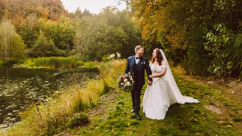 A bride and groom walk hand in hand along a grassy path beside a pond at one of the charming Snohomish wedding venues surrounded by lush green trees and autumn foliage The bride holds her dress and bouquet as they smile warmly at each other Snohomish Wedding Photography A bride and groom walk hand in hand along a grassy path beside a pond at one of the charming Snohomish wedding venues surrounded by lush green trees and autumn foliage The bride holds her dress and bouquet as they smile warmly at each other Snohomish Wedding Photography