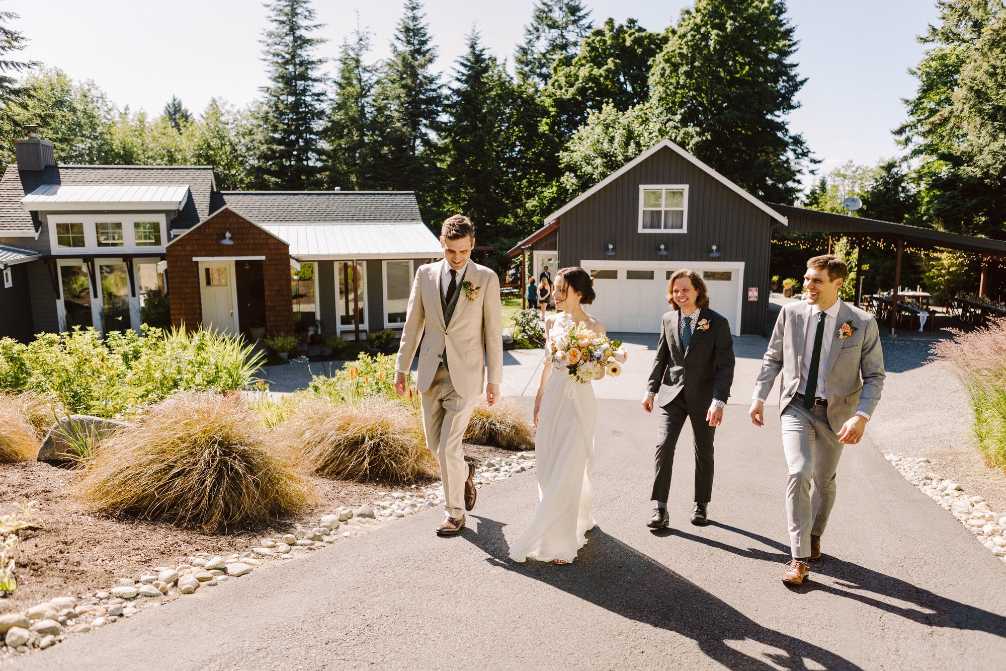 bride and groom and some of their guests walking up a hill at a home style wedding venue during their micro intentional wedding on camano island in the greater seattle area