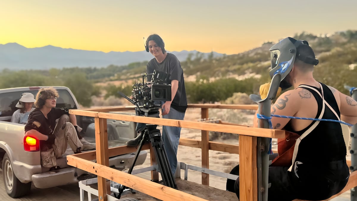 Film crew shooting on wooden platform with mountain sunset backdrop