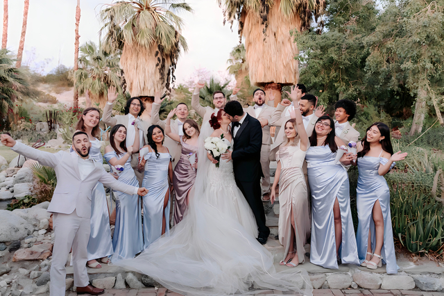 Full wedding party celebrating under palm trees at Bubbling Wells Oasis