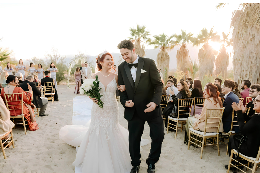 Joyful couple walking away from ceremony in golden desert light at Bubbling Wells Oasis