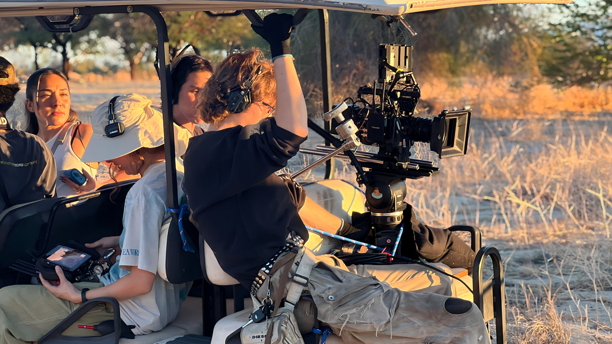 Film crew shooting from golf cart in desert terrain