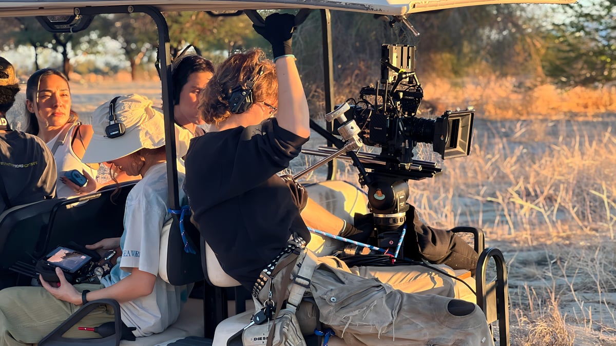 Film crew shooting from golf cart in desert terrain