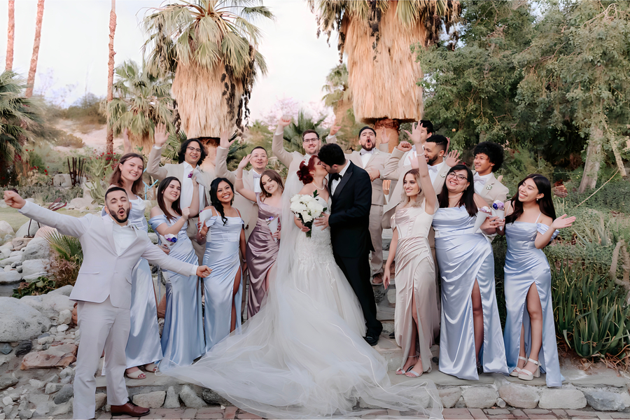 Wedding party in blue satin and champagne suits celebrating under the palms