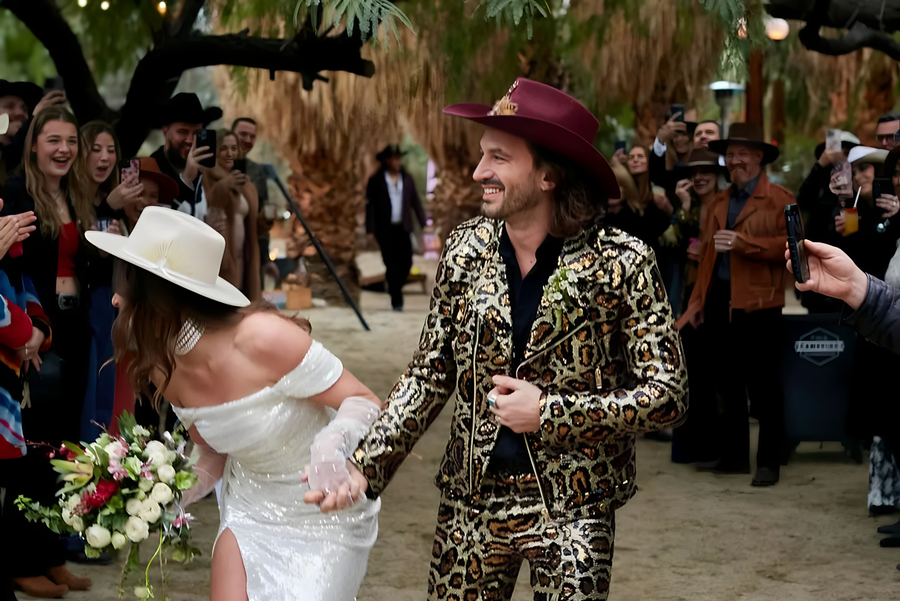 Groom in leopard print suit and bride recessing through cheering guests at Bubbling Wells Oasis