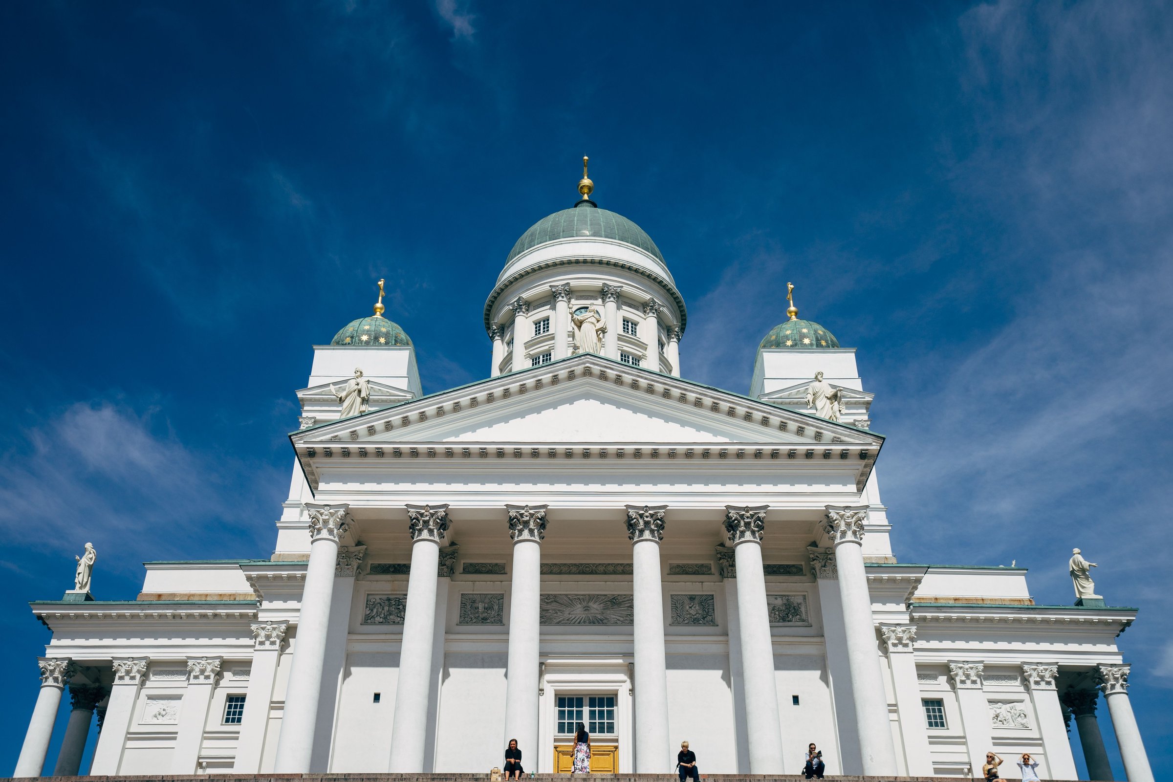 Katedral Helsinki berwarna putih dengan kubah hijau menjulang di bawah langit biru cerah