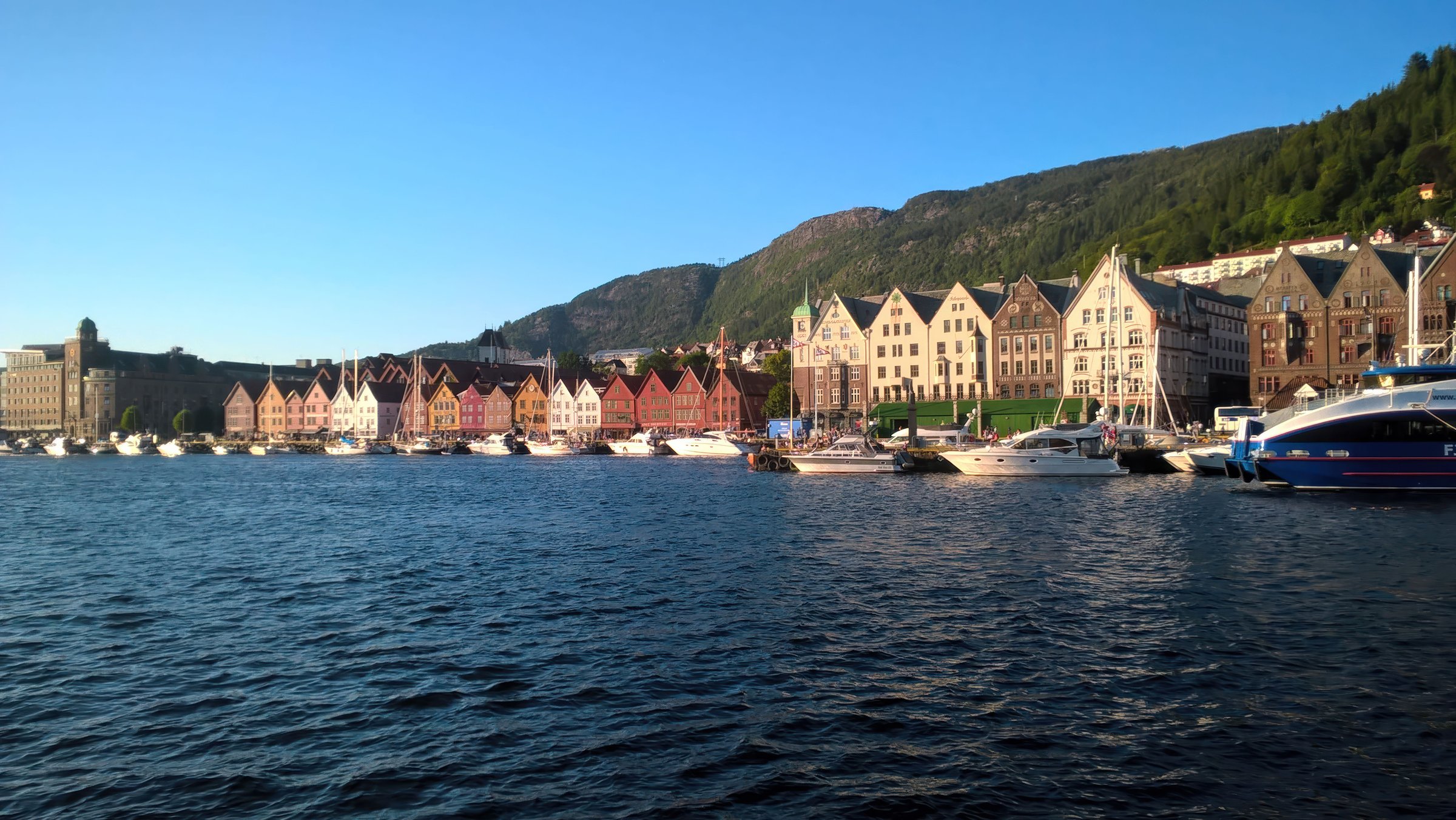 Deretan rumah kayu warna-warni Bryggen Bergen di tepi pelabuhan dengan langit biru cerah