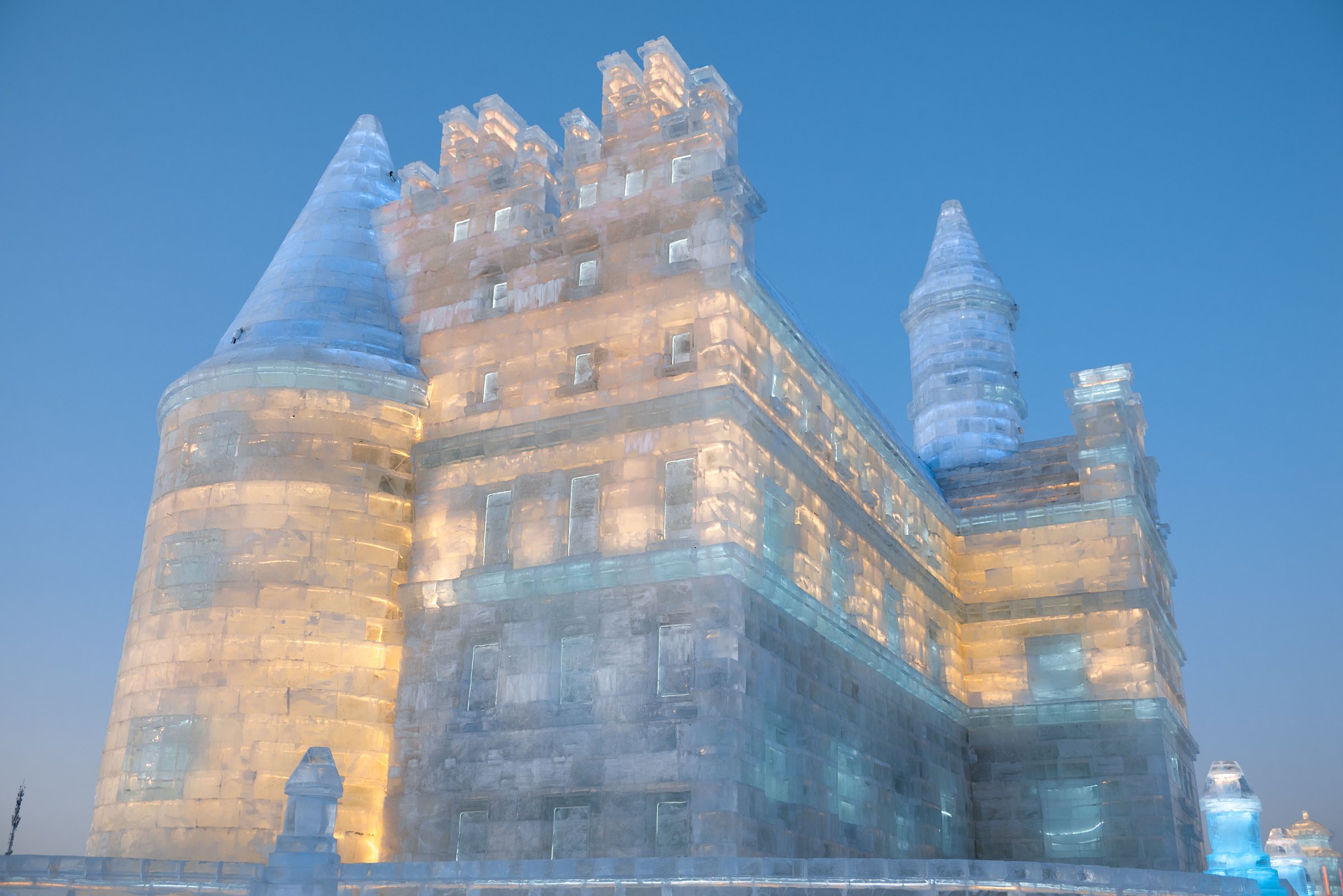 Istana es raksasa menyala warna-warni di ajang Harbin Ice Festival pada senja musim dingin