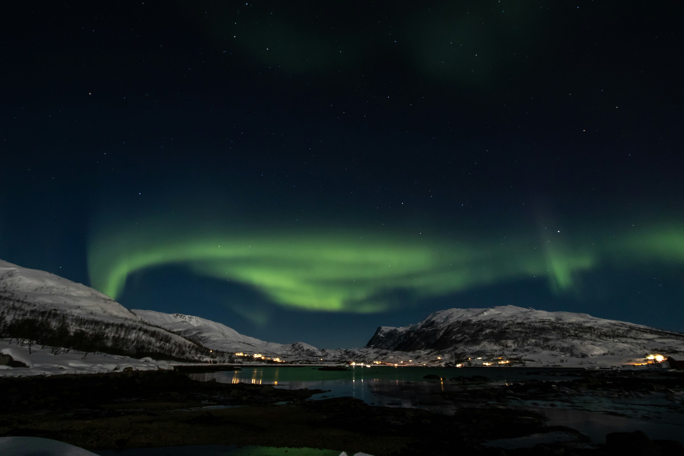 Aurora borealis hijau di atas desa nelayan bersalju, Tromsø