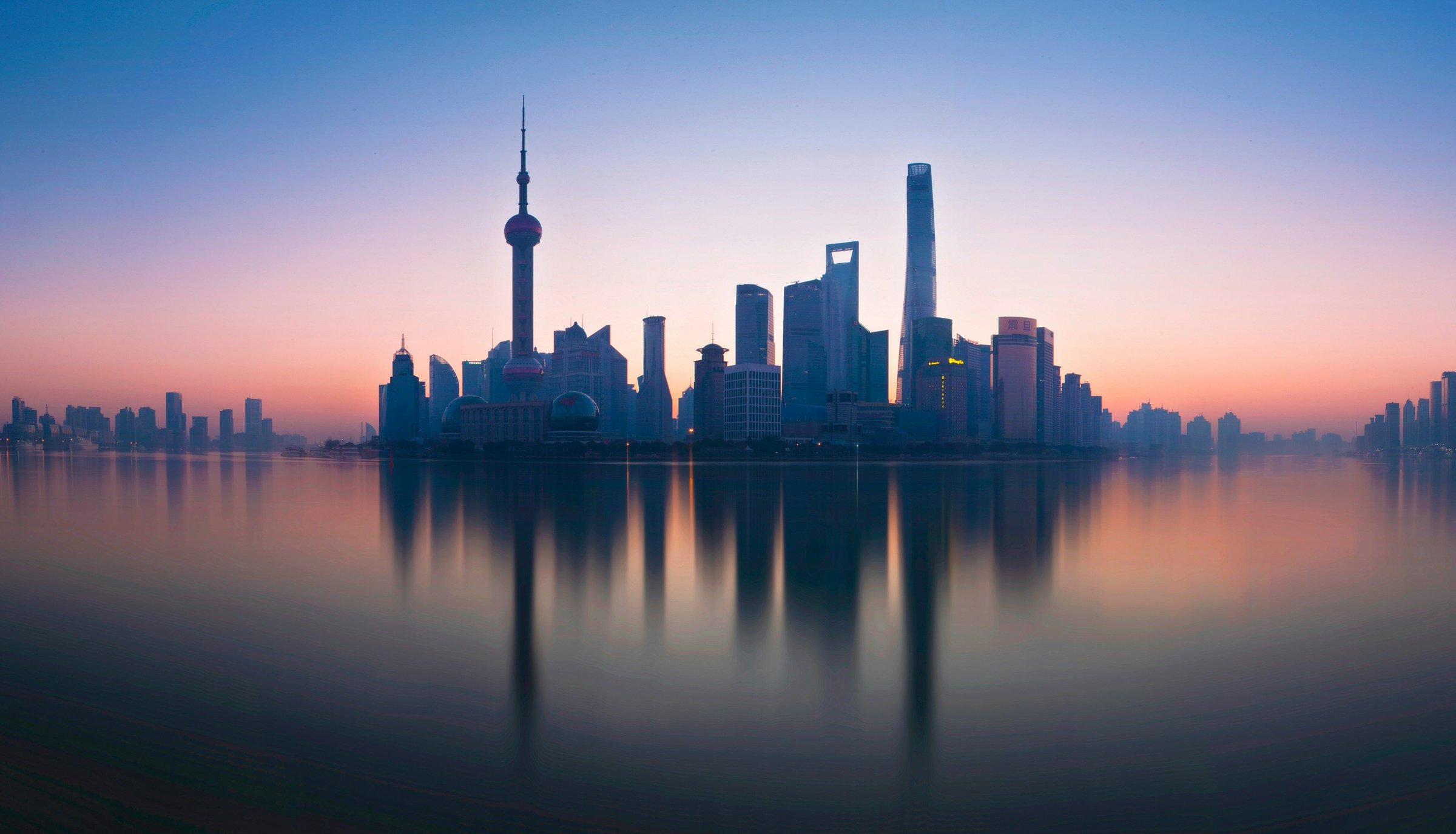 Skyline Pudong Shanghai saat fajar dengan refleksi tenang di Sungai Huangpu.