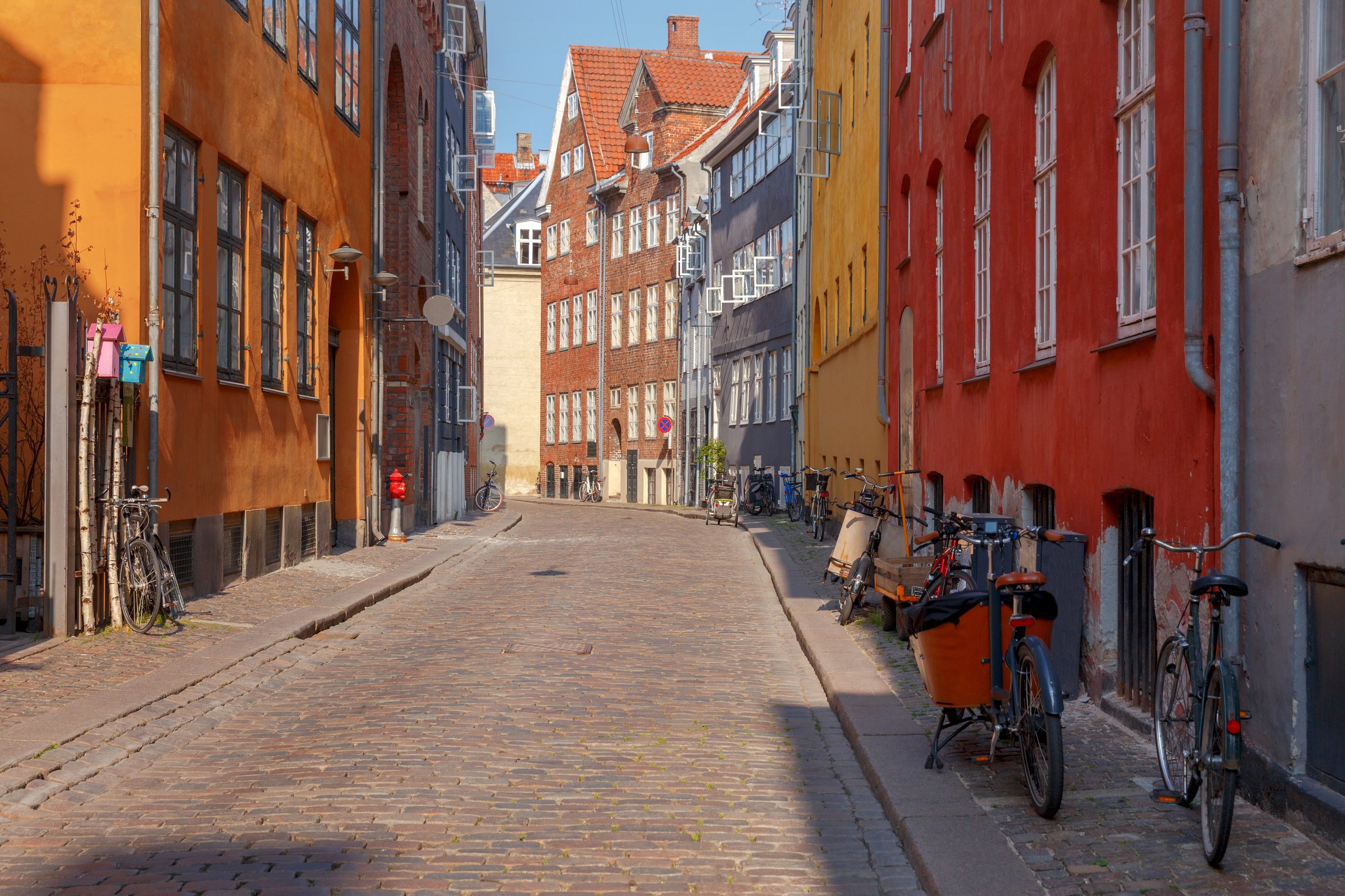 Jalan berbatu kota tua Copenhagen dengan rumah berwarna dan sepeda bersandar di tepi jalan