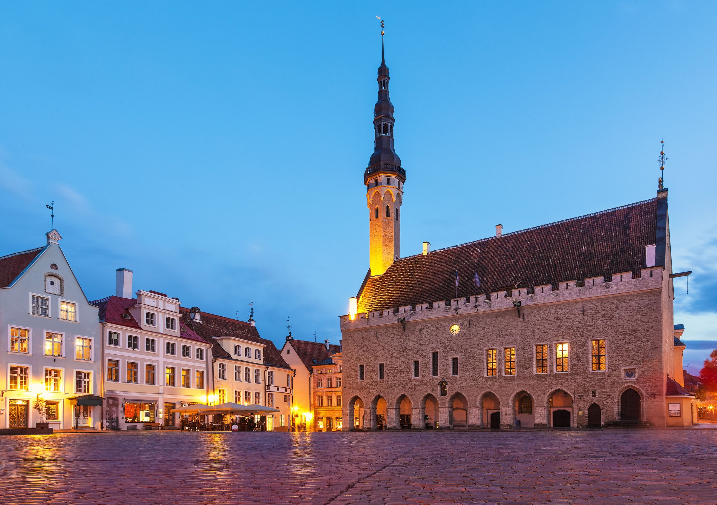 Balai kota abad pertengahan Tallinn di alun-alun berbatu saat senja dengan jendela bercahaya