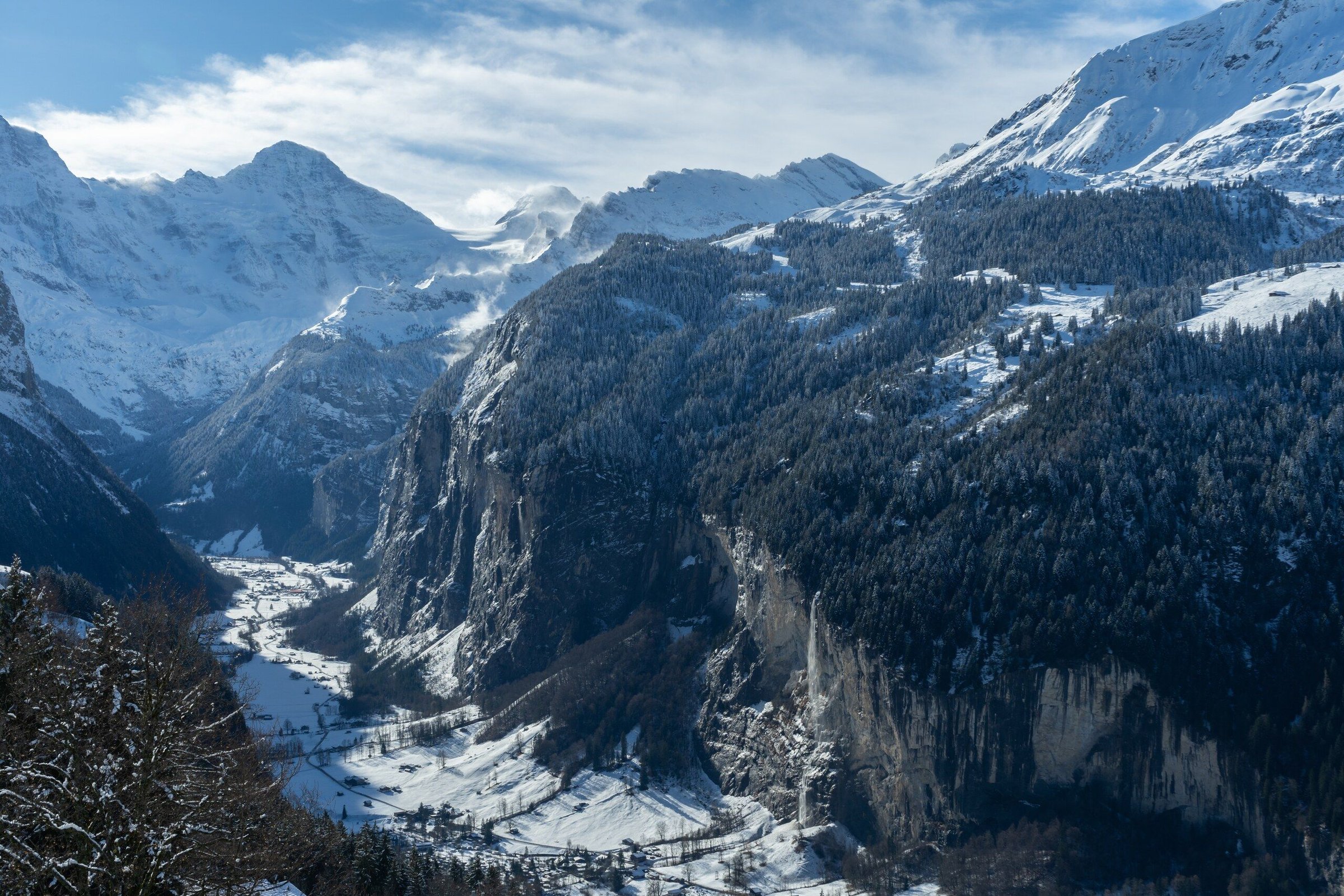 Lembah Lauterbrunnen dari udara dengan gunung bersalju dan sungai di dasar lembah pada hari cerah.