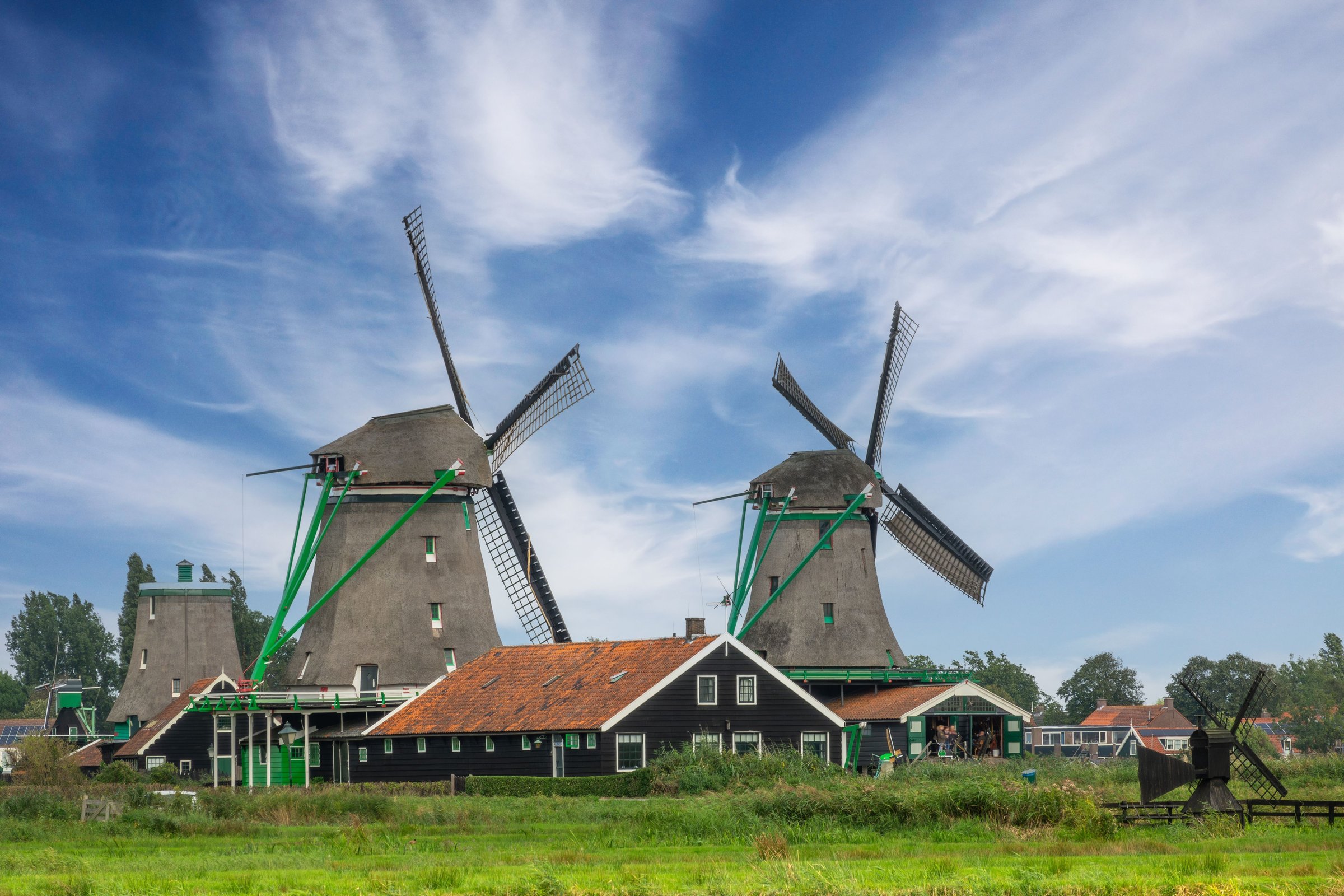 Kincir angin tua Zaanse Schans berdiri di tepi padang rumput hijau, Belanda
