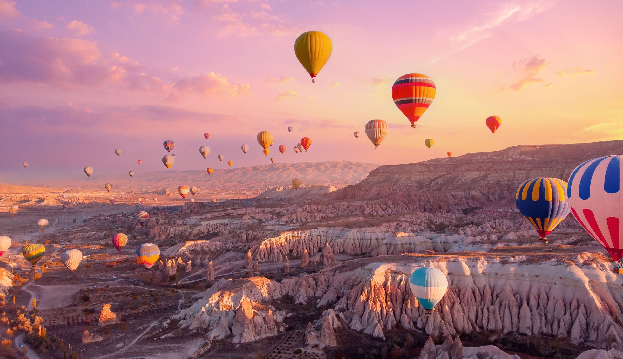 Puluhan balon udara warna-warni terbang di atas formasi batu Cappadocia, Turkiye