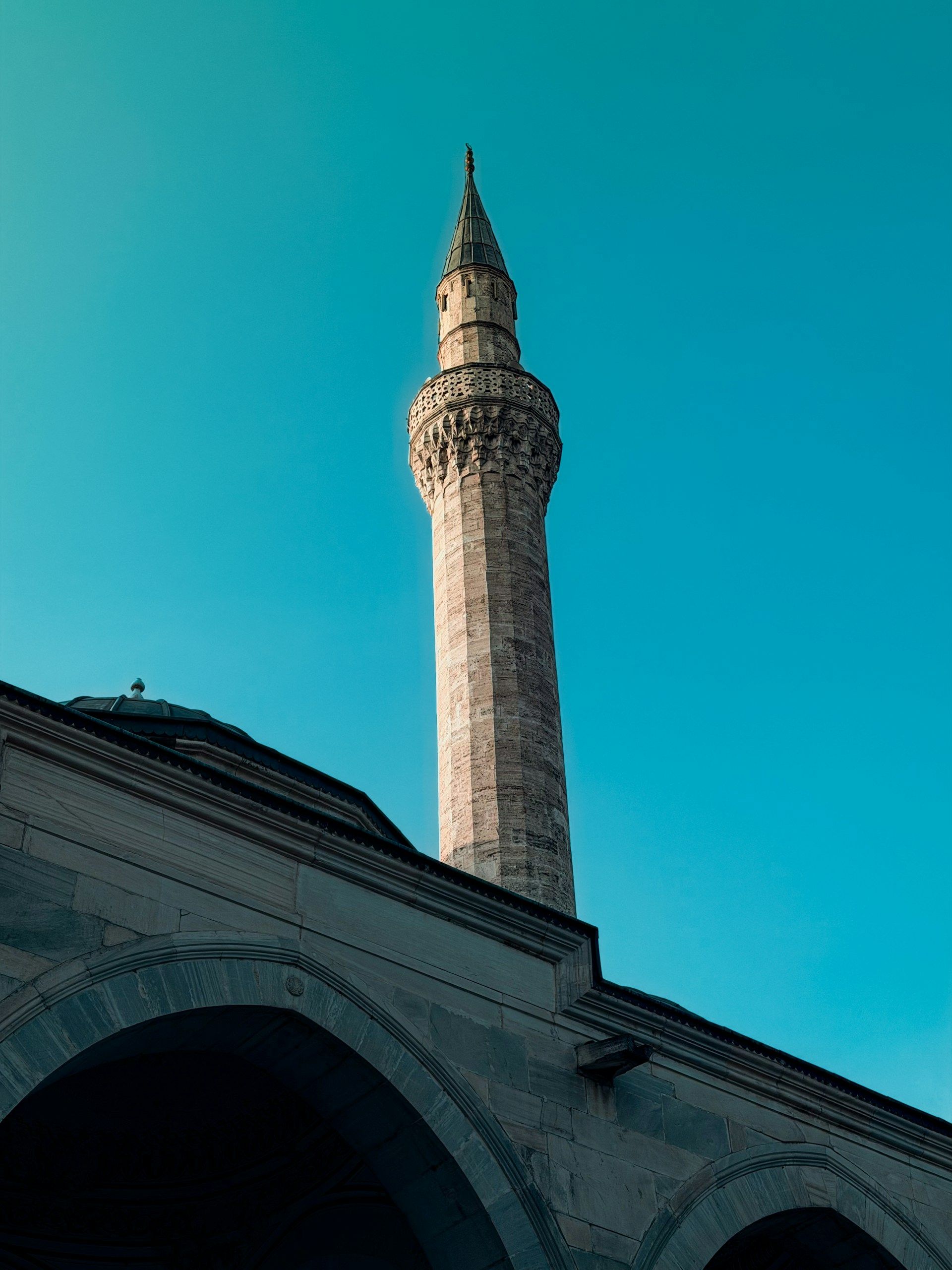 Menara batu Masjid Ottoman bersejarah di Makedonia Utara dengan detail muqarnas, langit biru cerah
