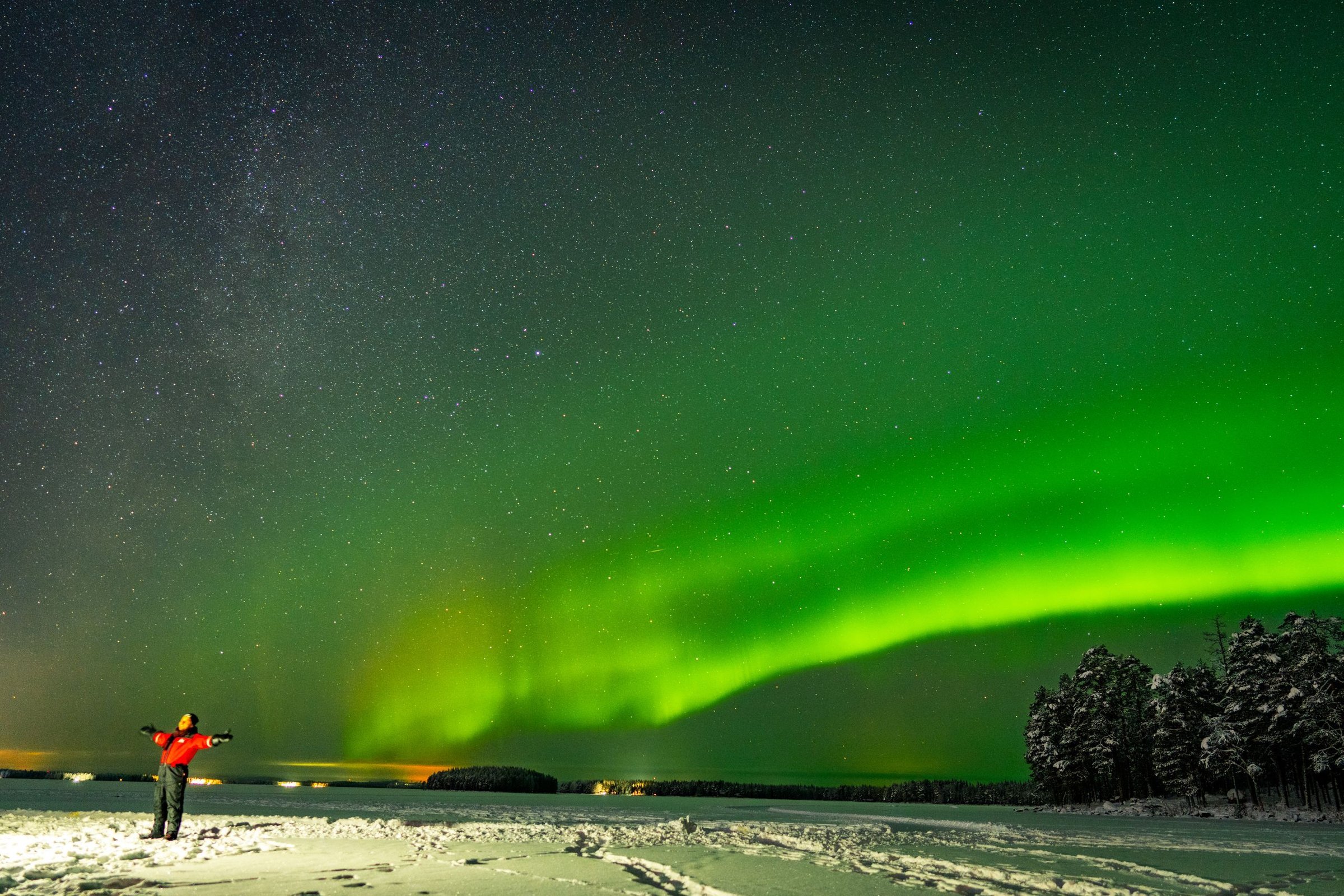 Aurora hijau dan langit berbintang di atas danau beku Lapland.