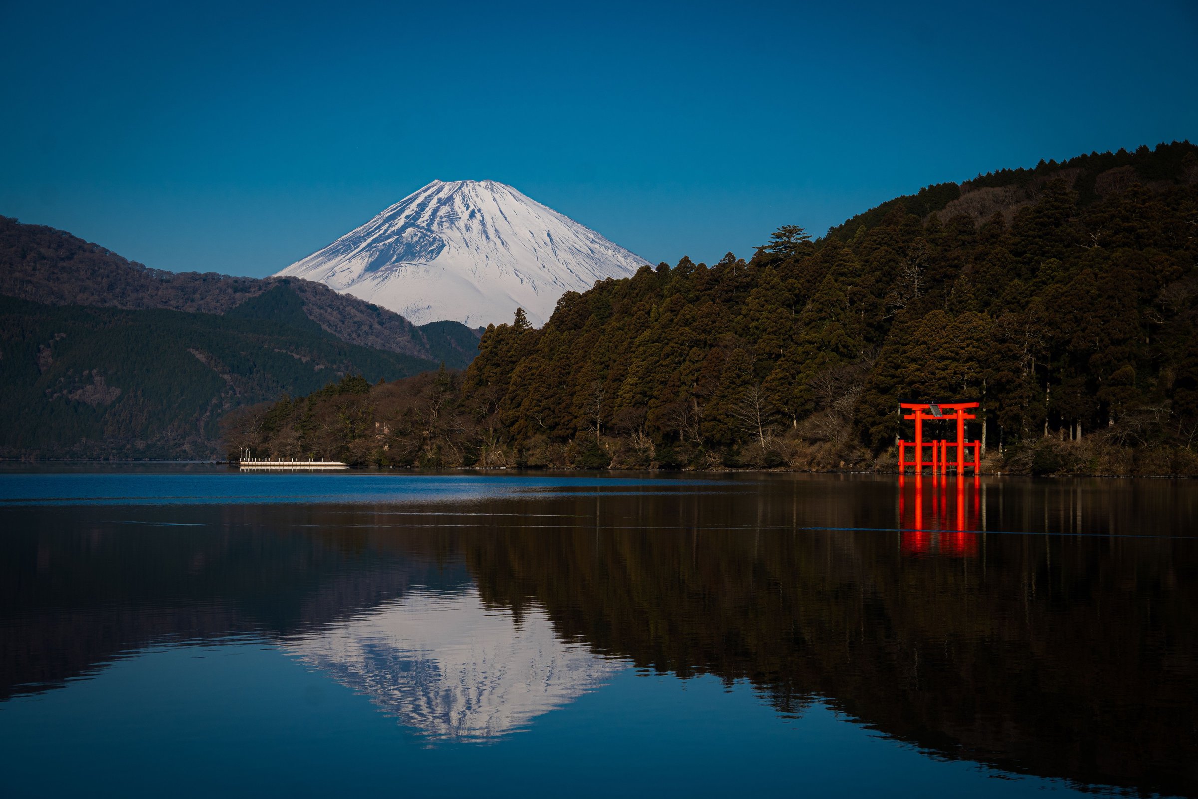 Torii merah Hakone terpantul di Danau Ashi dengan latar Gunung Fuji bersalju