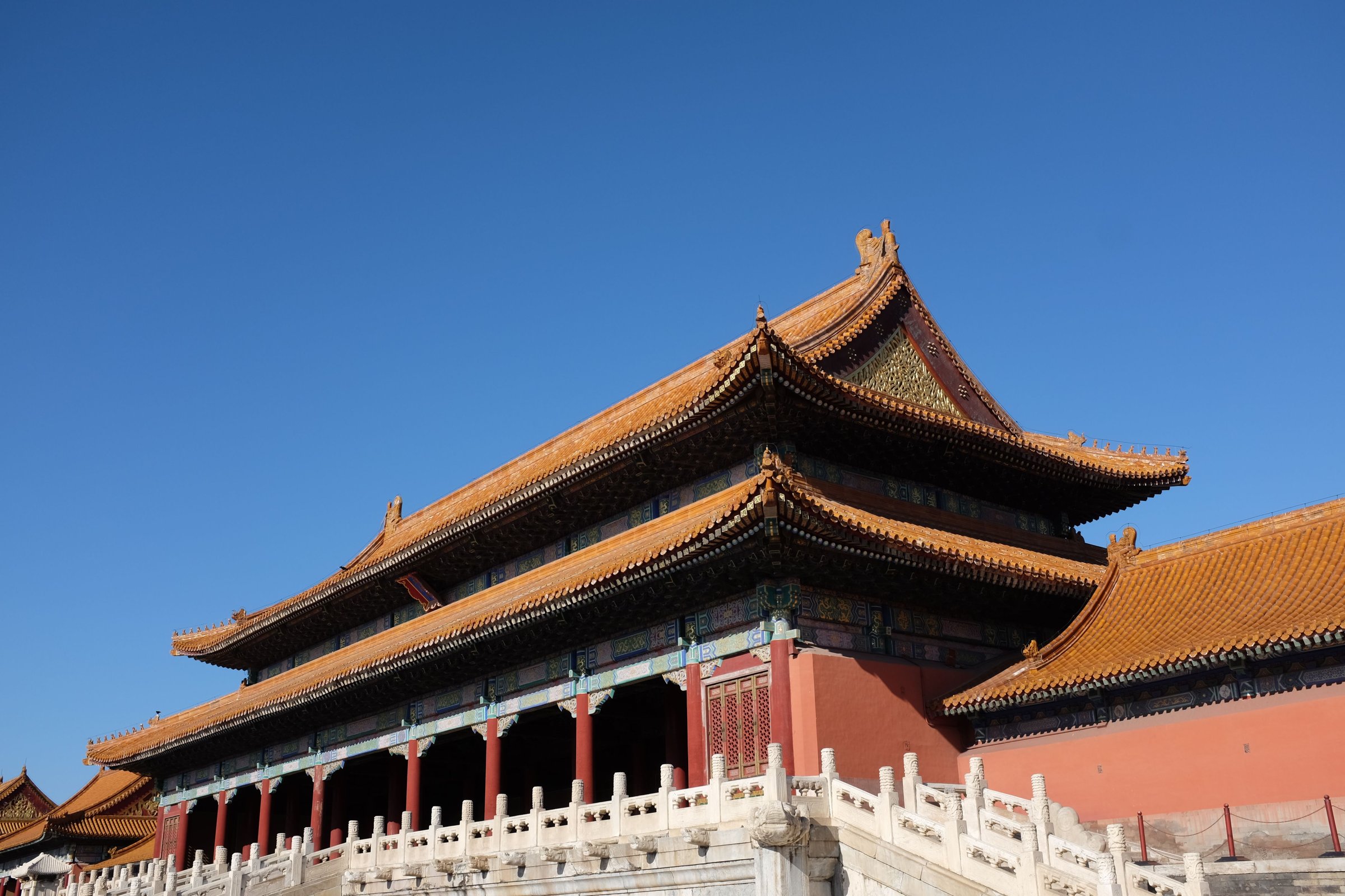 Atap keemasan berlapis dan tembok merah Forbidden City menjulang di bawah langit biru cerah